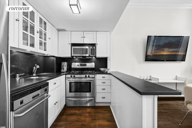 kitchen with sink, dark wood-type flooring, appliances with stainless steel finishes, white cabinets, and kitchen peninsula