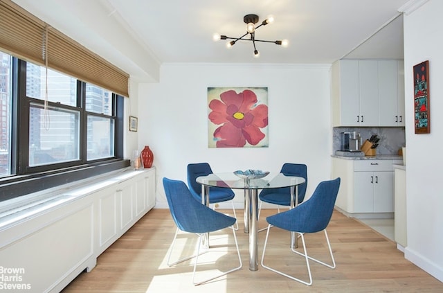 dining area featuring ornamental molding, an inviting chandelier, and light hardwood / wood-style floors