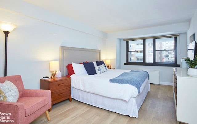 bedroom with radiator heating unit and light hardwood / wood-style flooring