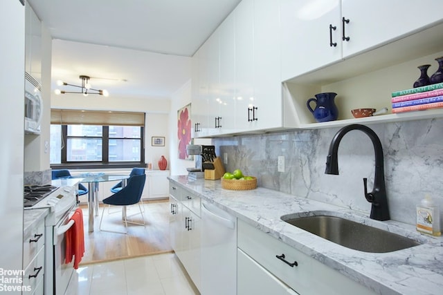 kitchen featuring sink, white appliances, white cabinetry, light stone counters, and decorative backsplash