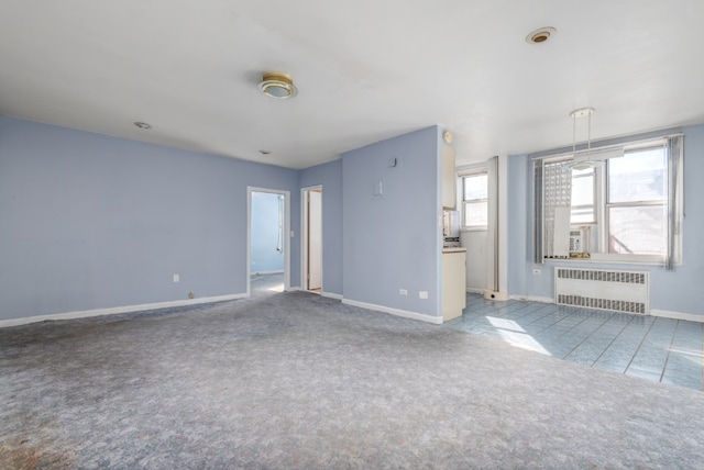 unfurnished living room with radiator, baseboards, and light colored carpet