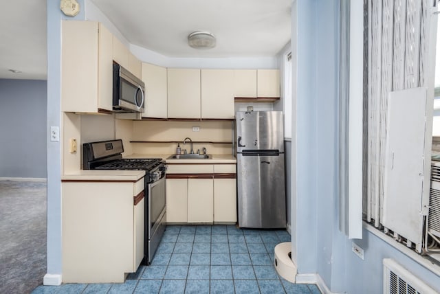 kitchen featuring visible vents, appliances with stainless steel finishes, cream cabinets, light countertops, and a sink