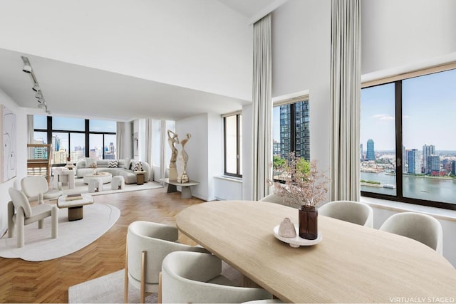 dining area with track lighting, a towering ceiling, and a city view