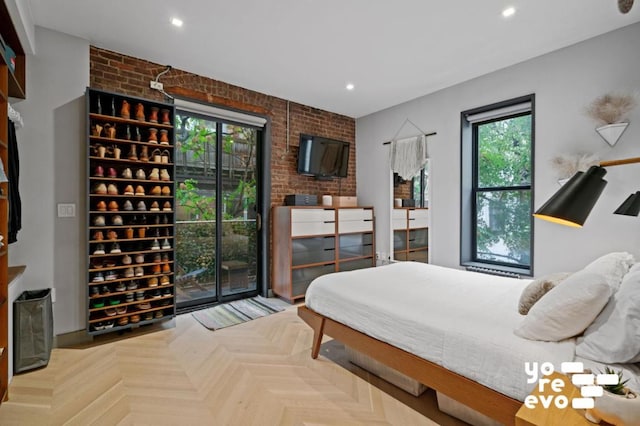 bedroom featuring multiple windows, brick wall, and parquet floors