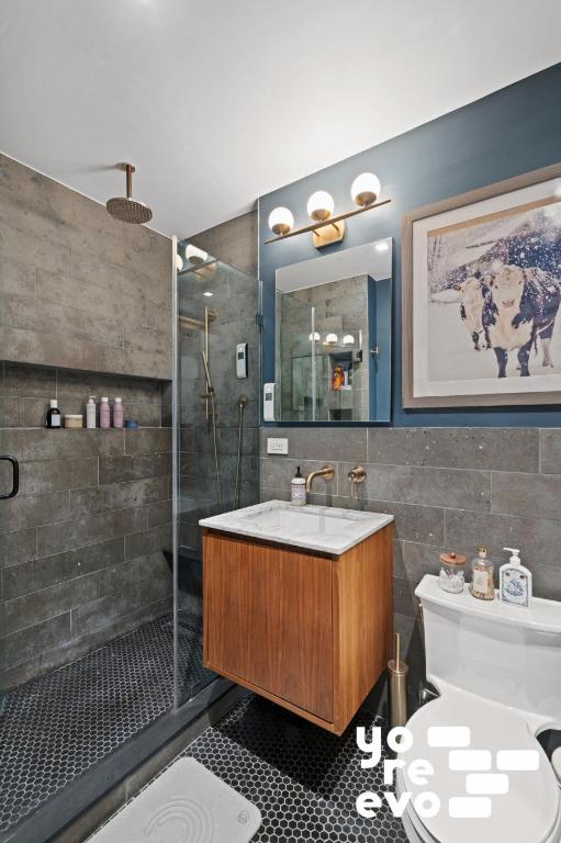 bathroom featuring toilet, vanity, tile walls, tile patterned flooring, and an enclosed shower