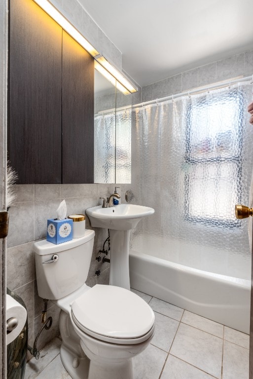 bathroom with toilet, a wealth of natural light, tile patterned flooring, and tile walls