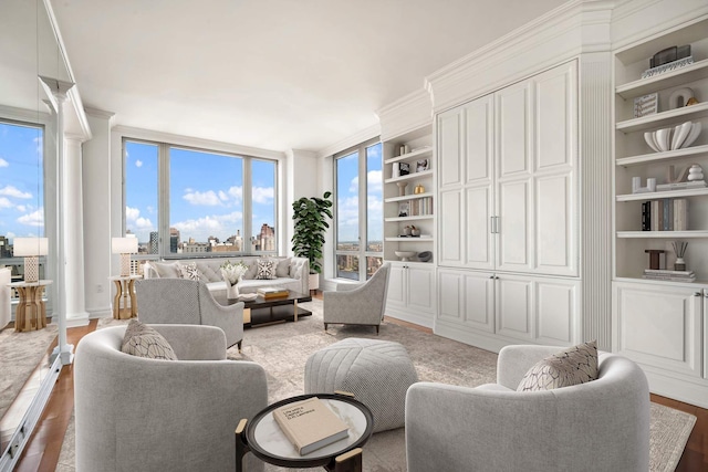 living area with built in shelves, a view of city, ornamental molding, and wood finished floors