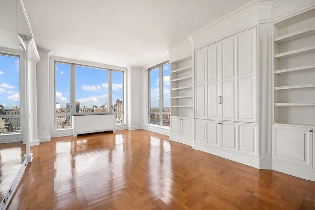 interior space featuring radiator, parquet floors, and decorative columns