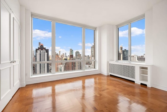 interior space with parquet flooring, plenty of natural light, and radiator heating unit