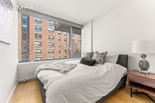 bedroom with wood-type flooring and baseboards