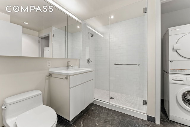 bathroom with a stall shower, stacked washer and clothes dryer, toilet, vanity, and recessed lighting