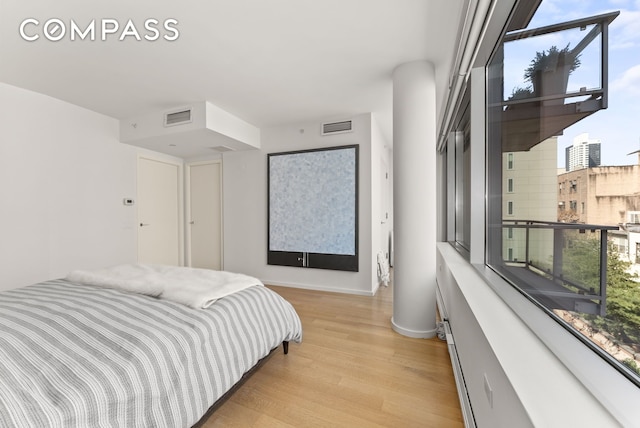 bedroom with light wood-style flooring, multiple windows, and visible vents