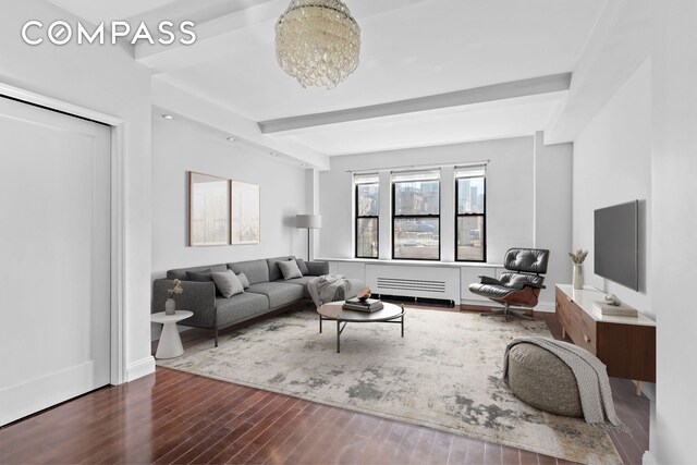 living room featuring dark hardwood / wood-style flooring, beamed ceiling, and an inviting chandelier