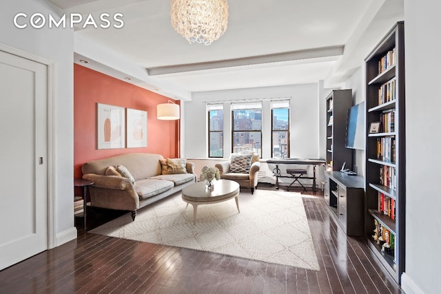 living room featuring dark wood-style flooring, a notable chandelier, beamed ceiling, and baseboards