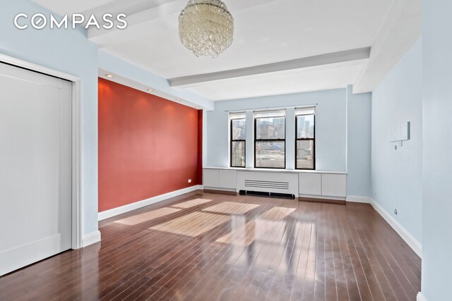 unfurnished room featuring radiator, beamed ceiling, baseboards, and wood finished floors