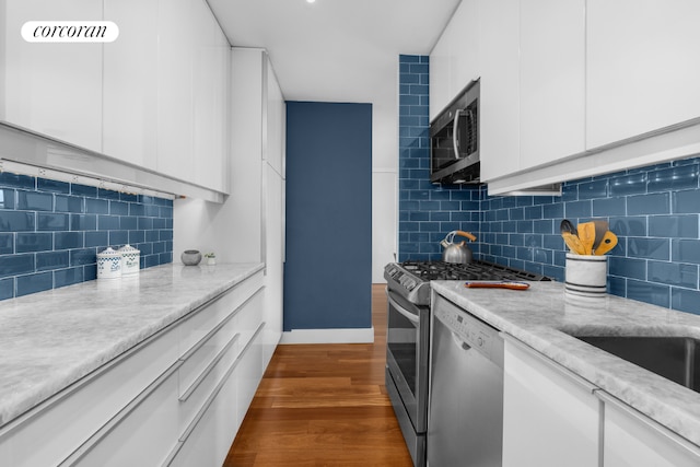 kitchen with decorative backsplash, white cabinets, dark hardwood / wood-style flooring, and stainless steel appliances