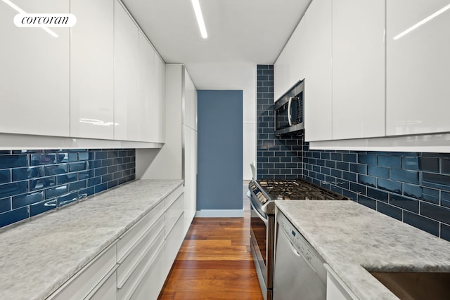 kitchen featuring stainless steel appliances, modern cabinets, white cabinets, dark wood finished floors, and decorative backsplash