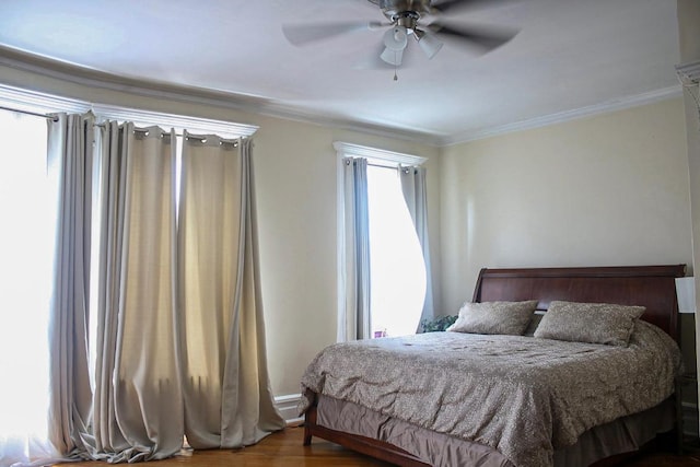 bedroom featuring ceiling fan, multiple windows, hardwood / wood-style flooring, and crown molding