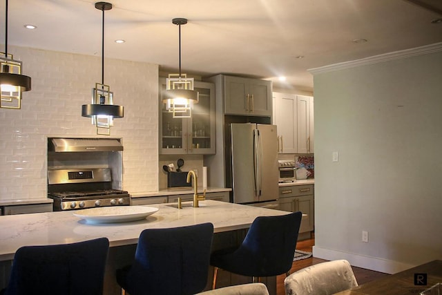 kitchen with stainless steel appliances, light stone countertops, ornamental molding, pendant lighting, and sink