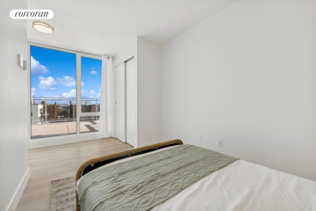 bedroom with expansive windows, visible vents, baseboards, and wood finished floors