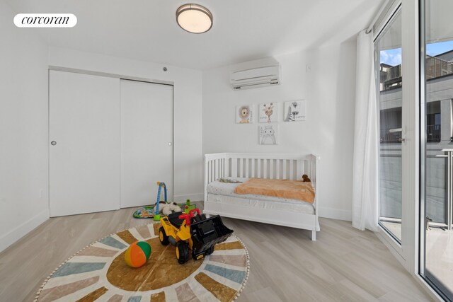 bedroom with wood finished floors, a wall mounted air conditioner, baseboards, and visible vents
