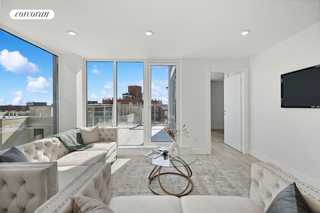 living area featuring visible vents, baseboards, a wall of windows, light wood-type flooring, and recessed lighting