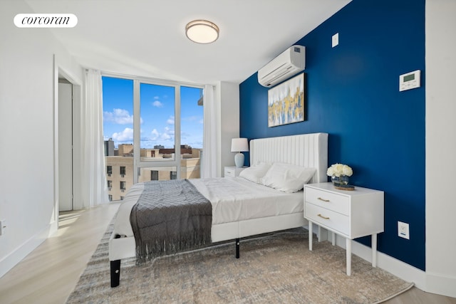 733 Ocean Pkwy Unit Ph9C, New York City, NY 11230 - bedroom featuring expansive windows, an AC wall unit, baseboards, and wood finished floors