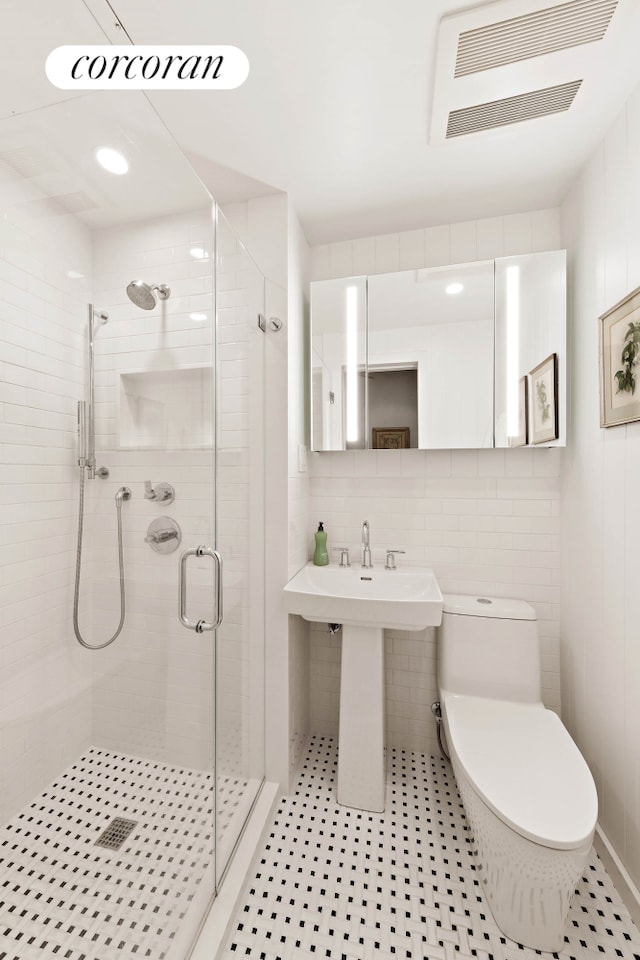 bathroom featuring toilet, a stall shower, visible vents, and a sink