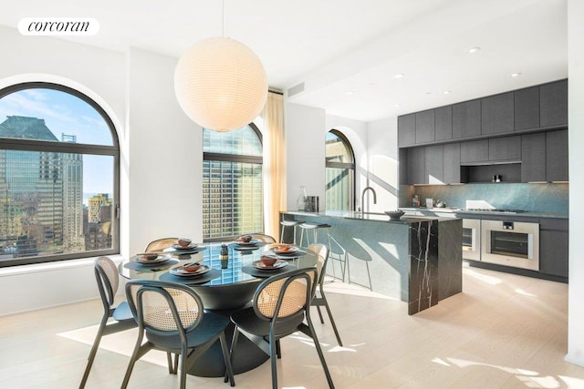 dining room featuring light wood-style flooring, visible vents, and a city view