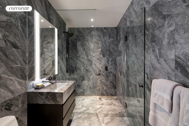 full bath with marble finish floor, tile walls, a marble finish shower, toilet, and vanity