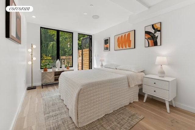 bedroom with floor to ceiling windows, light wood-style flooring, and baseboards