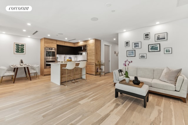 living area with light wood-style floors, visible vents, and recessed lighting