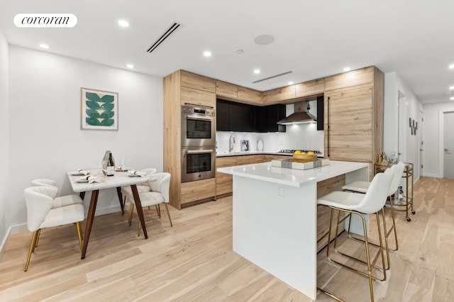 kitchen featuring visible vents, modern cabinets, a kitchen island, light countertops, and stainless steel double oven