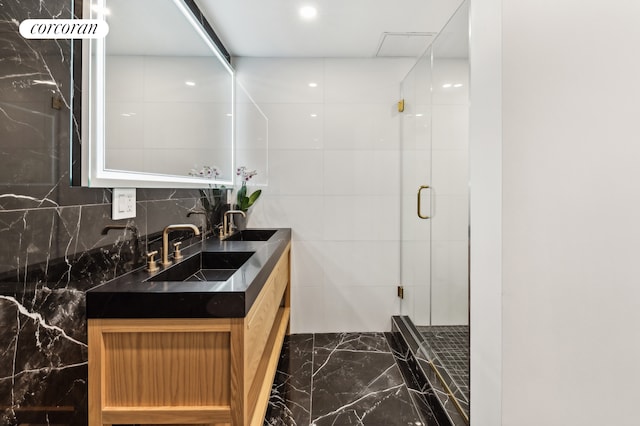 full bathroom featuring marble finish floor, double vanity, a sink, and a shower stall