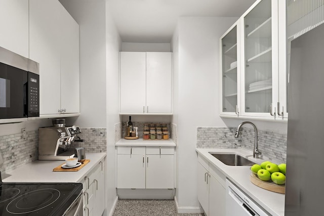 kitchen featuring stainless steel appliances, a sink, backsplash, white cabinetry, and light countertops