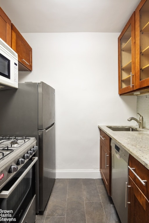 kitchen with appliances with stainless steel finishes, sink, and light stone counters