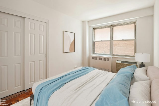 bedroom with radiator, a closet, an AC wall unit, and parquet flooring