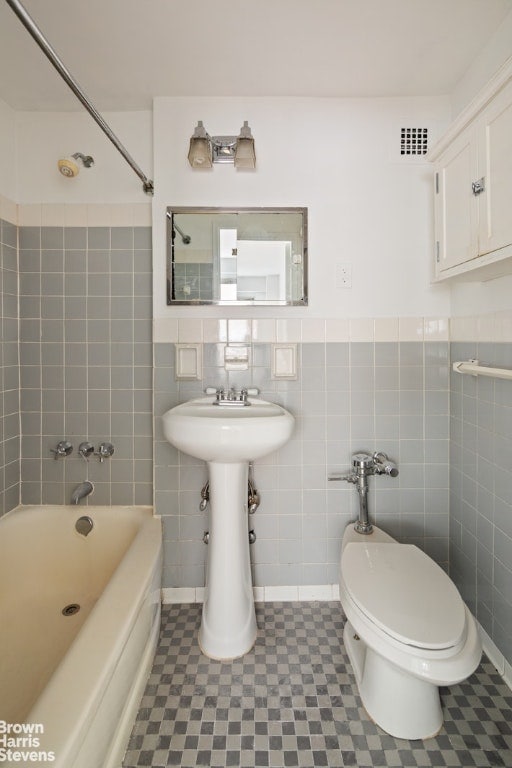 bathroom featuring washtub / shower combination, tile walls, toilet, and tile patterned flooring