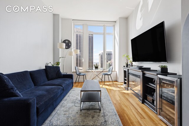 living room featuring indoor bar, beverage cooler, and hardwood / wood-style floors