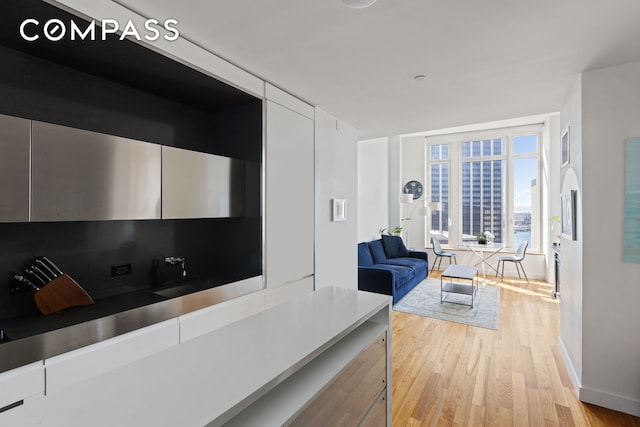 interior space with baseboards, modern cabinets, white cabinets, and light wood finished floors