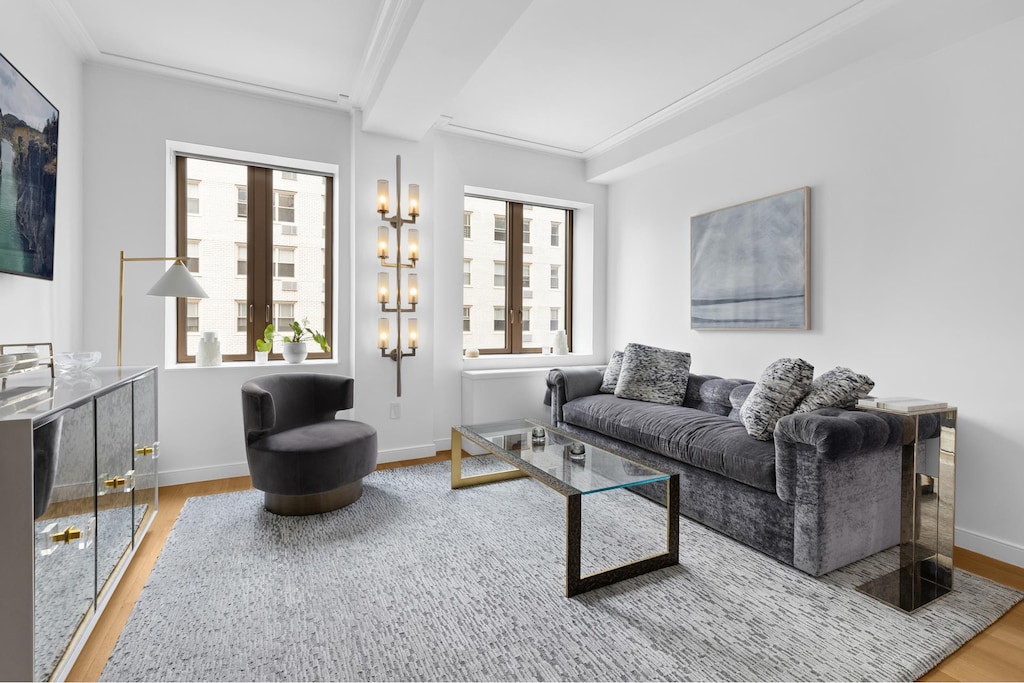 living room featuring beamed ceiling, ornamental molding, baseboards, and wood finished floors