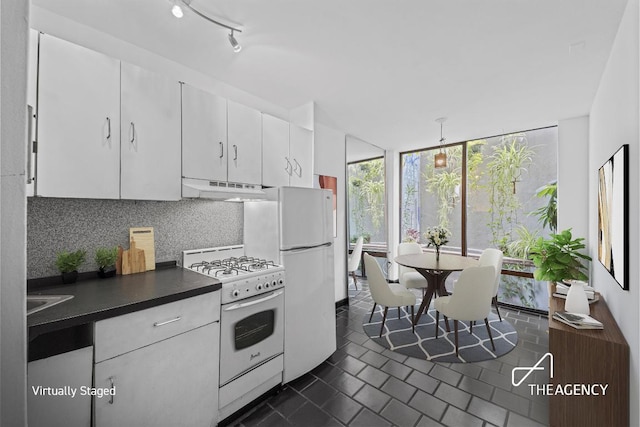 kitchen with tasteful backsplash, floor to ceiling windows, white appliances, white cabinetry, and dark tile patterned floors