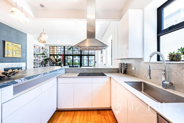 kitchen featuring white cabinetry, island range hood, black electric cooktop, hanging light fixtures, and sink