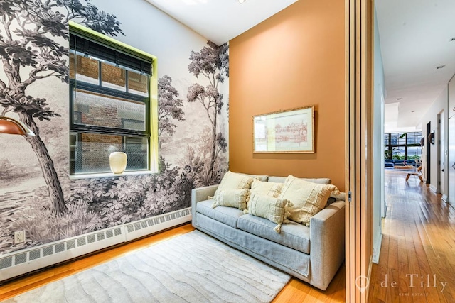 living area with a baseboard heating unit and hardwood / wood-style flooring