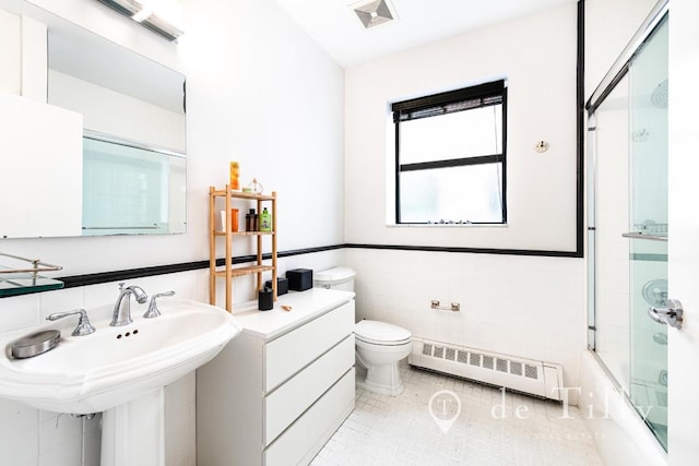 full bathroom featuring radiator, tile patterned flooring, bath / shower combo with glass door, tile walls, and toilet