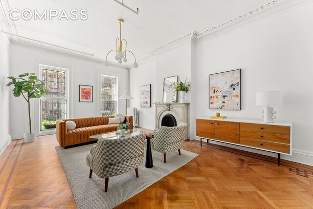 living room with ornamental molding, radiator, a notable chandelier, and parquet flooring