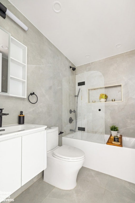 full bathroom featuring toilet, tile walls, tiled shower / bath, and vanity