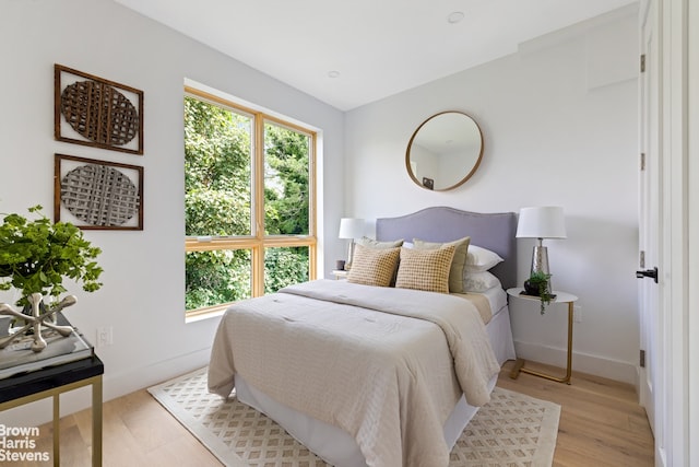 bedroom with baseboards, multiple windows, and light wood-style floors