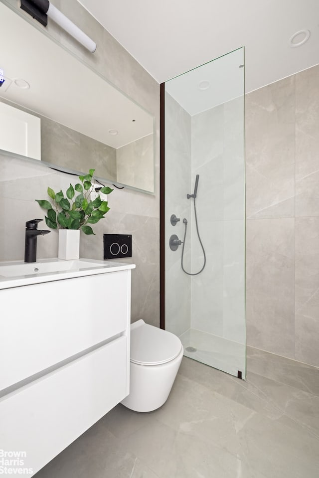 bathroom with a walk in shower, toilet, vanity, and tile walls