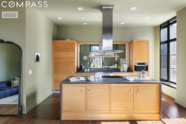 kitchen with a kitchen island, light brown cabinetry, island range hood, and oven